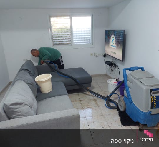 אדם מנקה ספה עם מכונת ניקוי מקצועית
